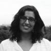 Foto en blanco y negro de una mujer sonriente de pelo castaño y lentes. 