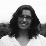 Foto en blanco y negro de una mujer sonriente de pelo castaño y lentes. 